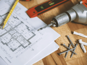 superfície com furadeira, papel, parafusos e brocas