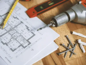 superfície com furadeira, papel, parafusos e brocas