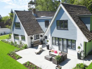 imagem de casa com telhado triangular e área com mesa na frente da casa perto de gramado