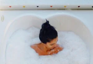 Mulher com cabelo preso aproveita spa em casa na hidro