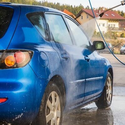 Homem lava carro azul com a melhor lavadora de alta pressão