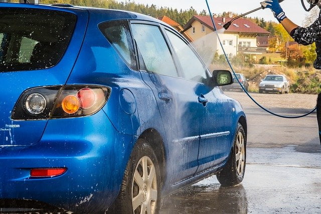 Homem lava carro azul com a melhor lavadora de alta pressão