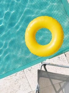 Piscina com revestimento claro, na superfície uma boia redonda amarela com furo no meio