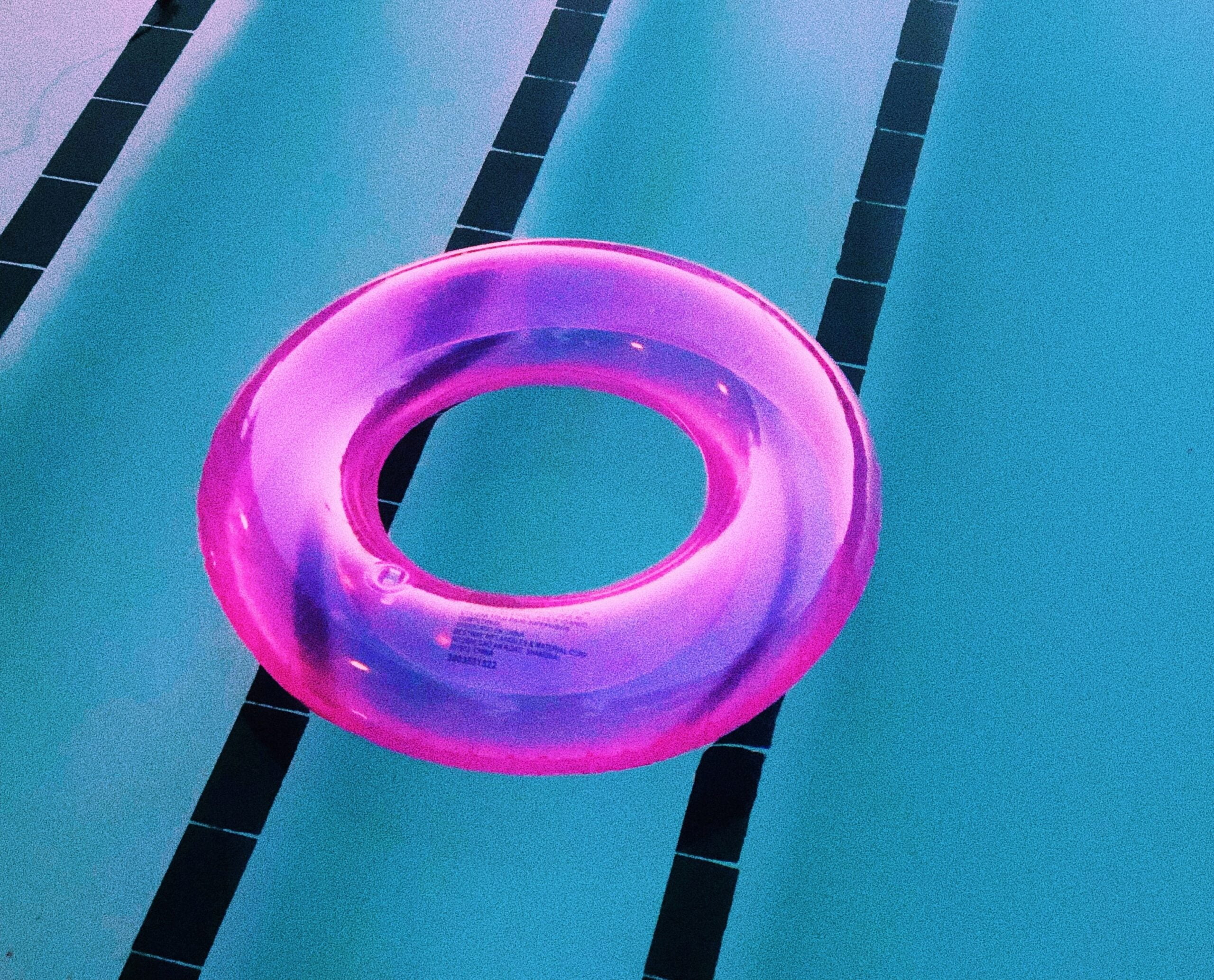Parte de uma piscina com boia lilás flutuando em sua superfície