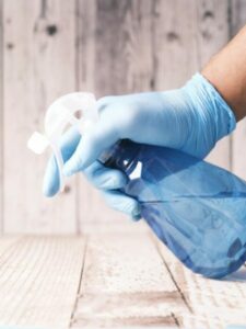 NR 24. Mão segurando um frasco e higienizando o local.