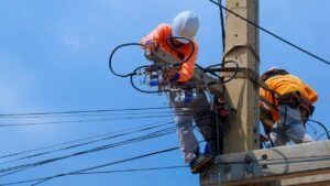 funcionário enel trabalhando em poste de eletricidade