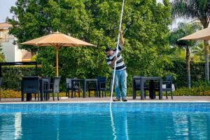 homem limpando a água da piscina