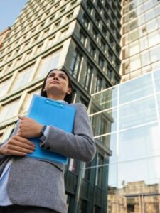 sindicos_low-angle-businesswoman-holding-clipboard-city
