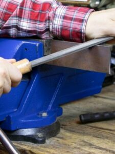 Homem usando morsa de bancada.